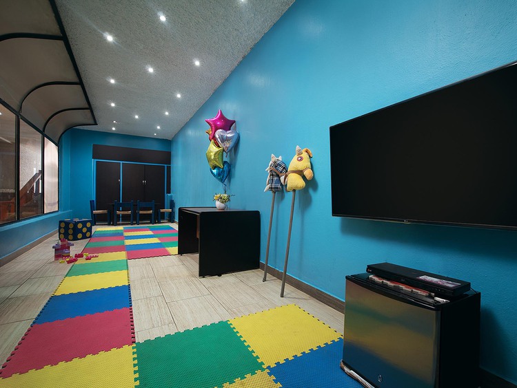 Mounted TV, colorful floor mat, and balloons in room with blue wall