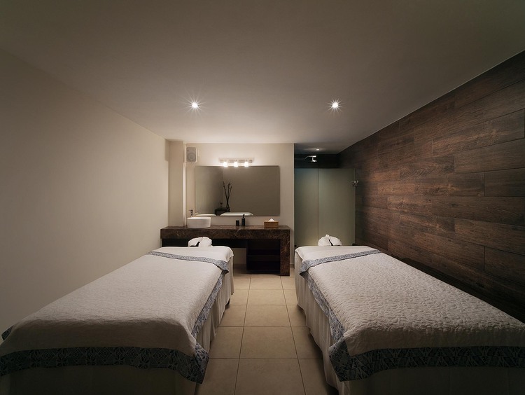 Two massage tables with white blankets in dimly lit spa room