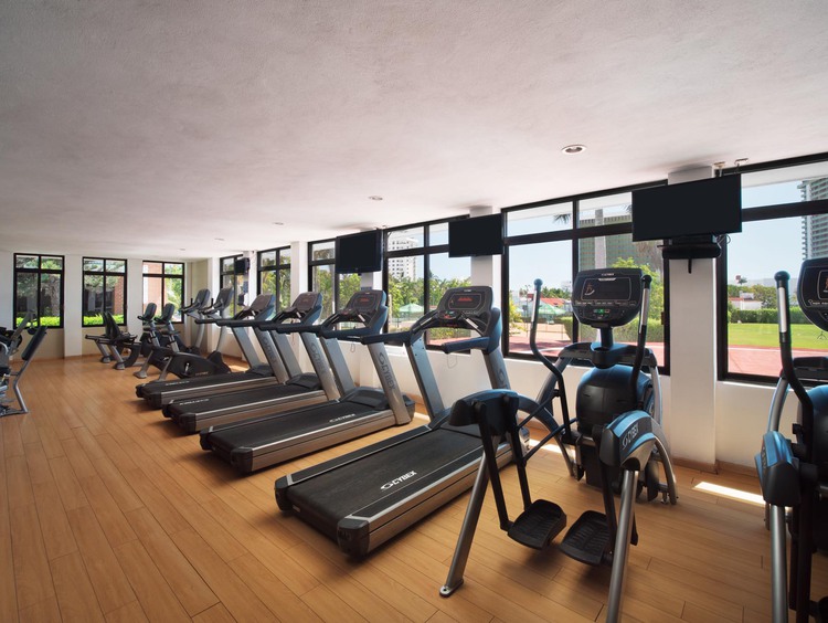 Elliptical machines in fitness room with mounted TVs