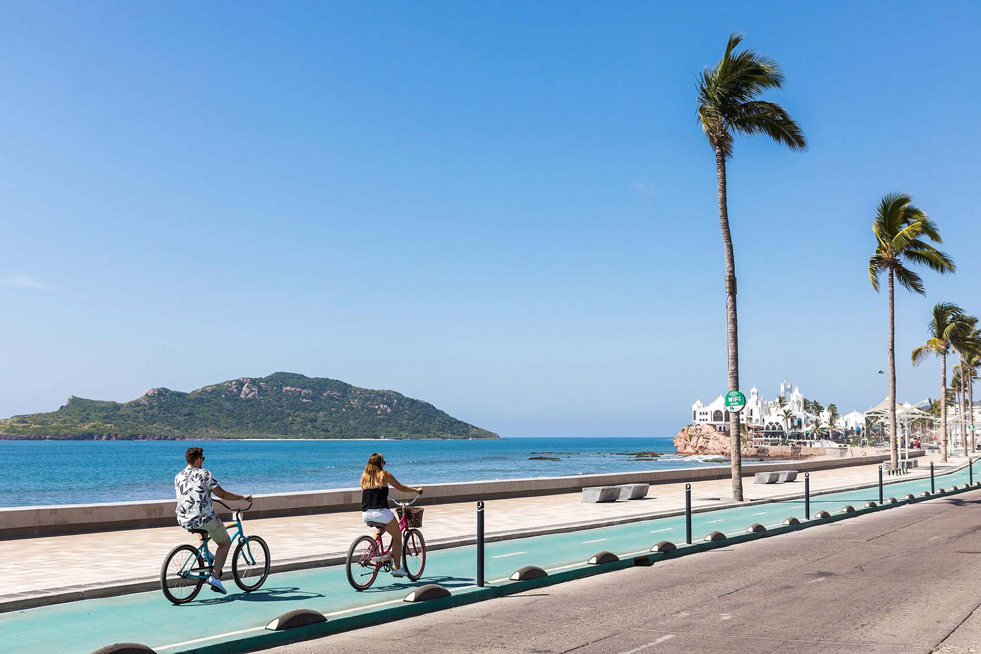 People riding bikes on pier on beach 