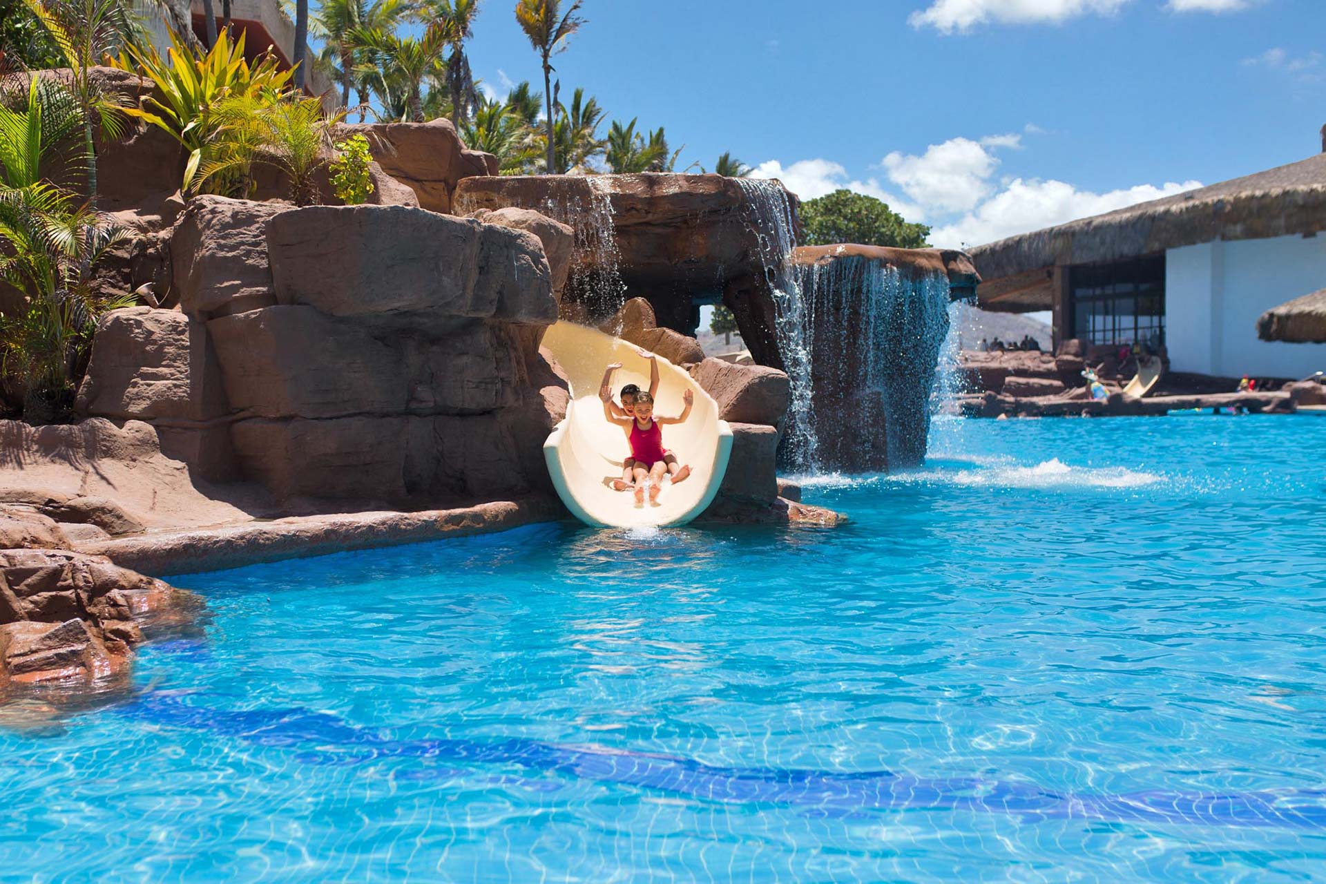 Kids sliding down slide into pool