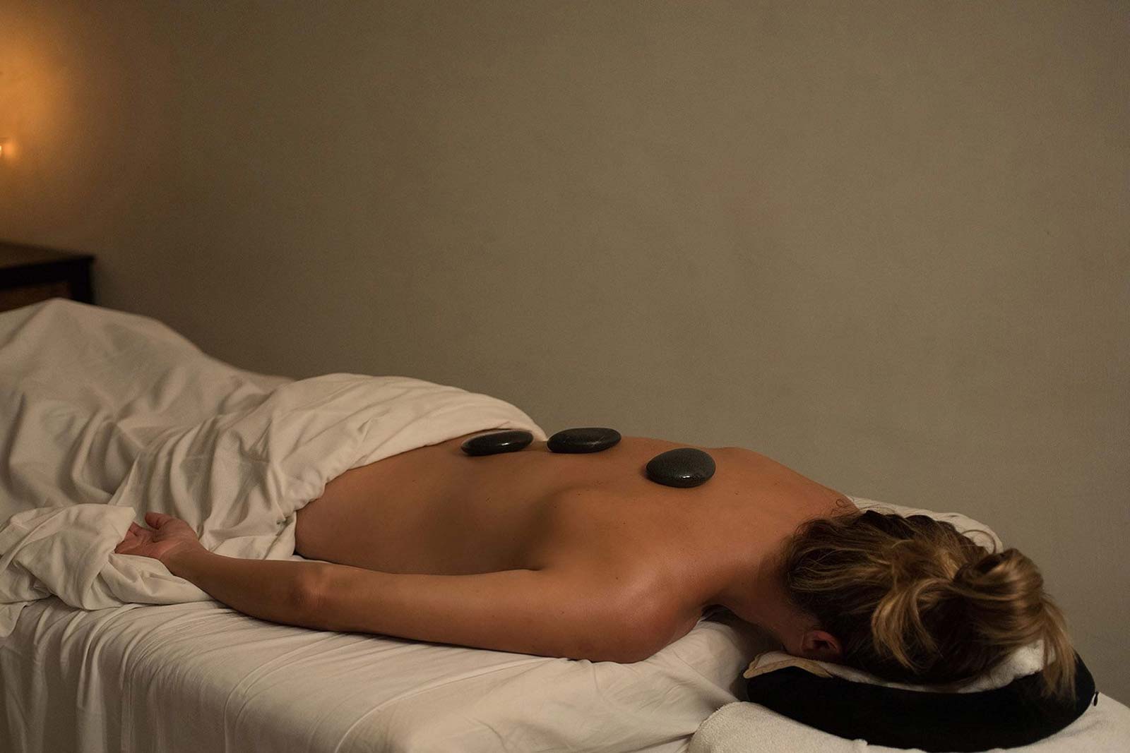 Woman laying facedown with hot stones on her back